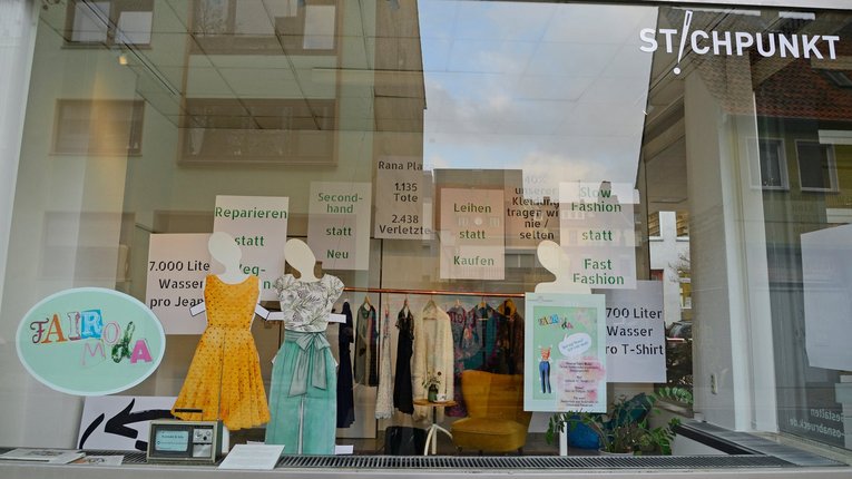 Blick in ein Schaufenster mit einer Ausstellung zum Thema "Faire Mode"